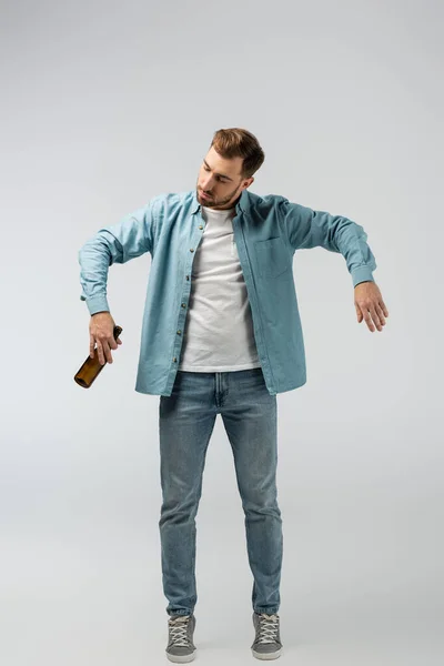 Jonge Man Poseren Als Marionet Met Fles Bier Geïsoleerd Grijs — Stockfoto