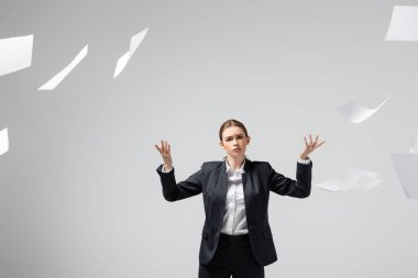displeased businesswoman in suit throwing papers in air isolated on grey clipart