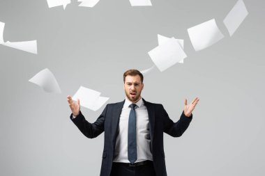 displeased businessman in suit throwing papers in air isolated on grey clipart