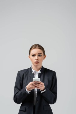 Gri üzerinde izole akıllı telefon kullanan üzgün genç iş kadını