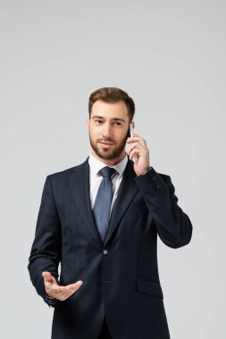 Takım elbiseli yakışıklı bir işadamı gri bir telefondan konuşuyor.