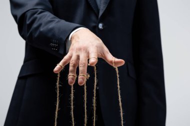 Takım elbiseli kuklacının kısmi görüntüsü, parmakları gri renkte izole edilmiş.