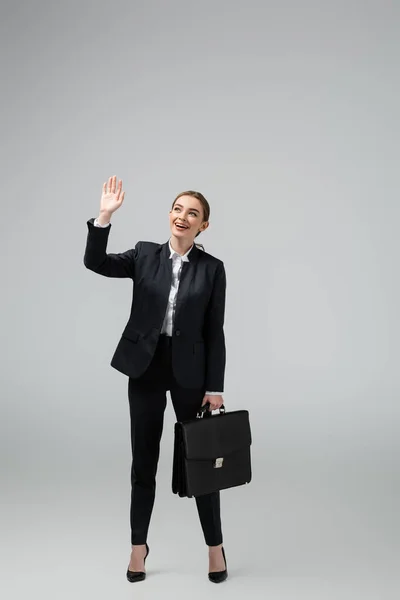 Jovem Empresária Alegre Com Mala Couro Acenando Mão Isolada Cinza — Fotografia de Stock