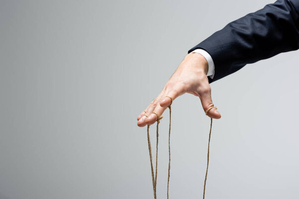 cropped view of puppeteer with strings on fingers isolated on grey