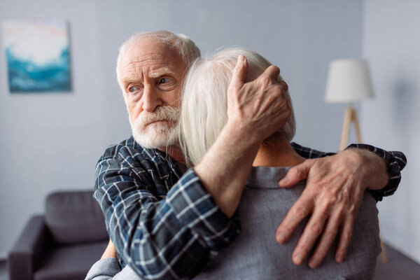 senior, sad man hugging wife, sick on dementia, and looking away