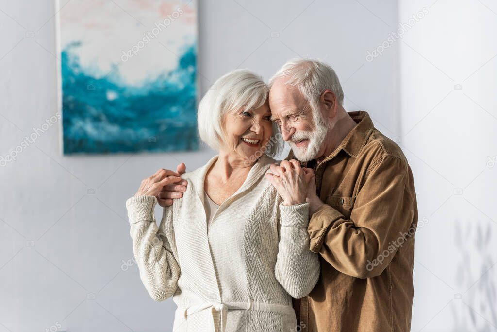 cheerful senior man touching shoulders of happy wife 