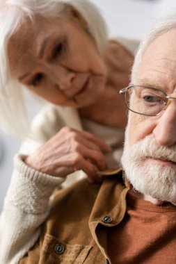 selective focus of senior woman looking at husband with dementia disease clipart