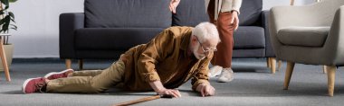 partial view of woman helping fallen senior husband to get up from floor, horizontal concept clipart