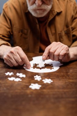 Bunama rehabilitasyonu için yapboz oynayan yaşlı bir adamın kırpılmış görüntüsü
