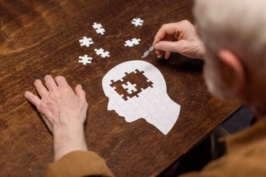 high angle view of senior man collecting jigsaw puzzle as dementia rehab clipart