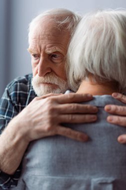 Yaşlı adam, bunaklık çekiyor, karısına sarılıyor ve başka tarafa bakıyor.