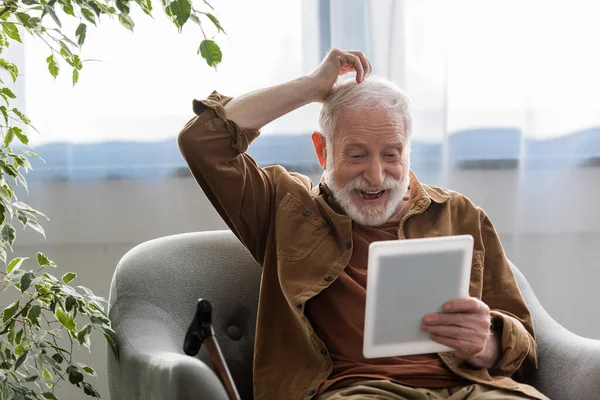 Alegre Hombre Mayor Tocando Tenía Mientras Utiliza Tableta Digital Sillón — Foto de Stock