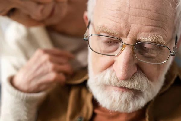 selective focus of senior woman looking at husband, sick on dementia