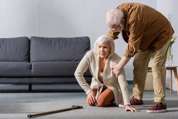 Senior Man Hjälpa Fru Sitter Golvet Nära Promenadkäpp — Stockfoto