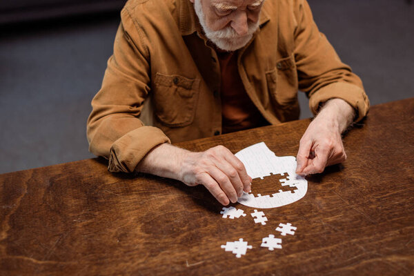 high angle view of senior man playing jigsaw puzzle as dementia therapy