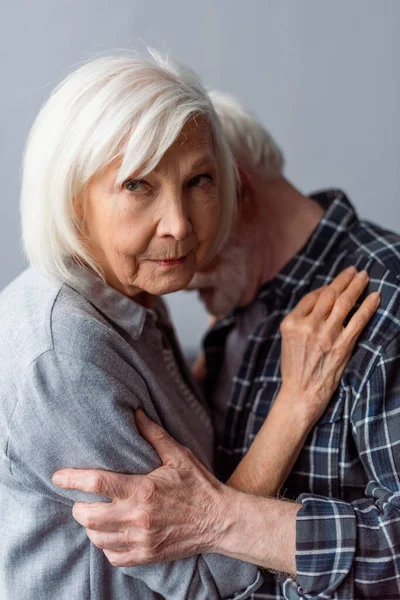 Verärgerte Seniorin Blickt Die Kamera Während Sie Ihren Demenzkranken Mann — Stockfoto