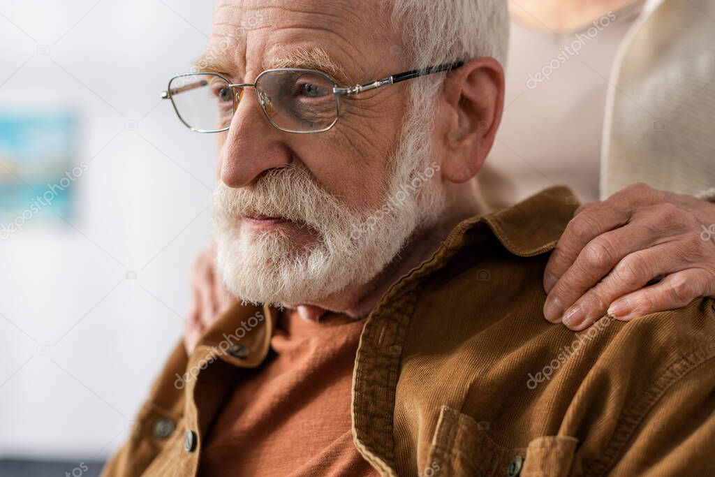 cropped view of woman touching shoulders of senior husband, sick on dementia