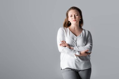 attractive, confident overweight girl posing with crossed arms isolated on grey clipart