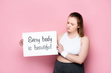 serious overweight holding placard with every body is beautiful inscription on pink clipart