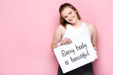 cheerful overweight girl holding placard with every body is beautiful lettering on pink clipart