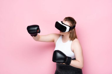 Artı VR kulaklıklı ve boks eldivenli kız. Pembe üzerinde dövüşüyormuş gibi yapıyor.