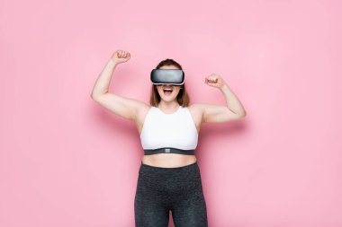 Heyecanlı boy artı vr kulaklıklı kız ve spor giyim yarışmasının birincisi pembe jest yapıyor.