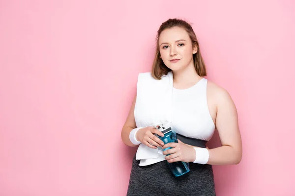 Sorridente Ragazza Sovrappeso Con Asciugamano Sulla Spalla Tenendo Bottiglia Sportiva — Foto Stock