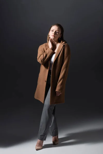 Full length view of trendy plus size girl touching neck while posing on grey — Stock Image Full Length View Trendy Size Girl Touching Neck While Posing Royalty Free Stock Images