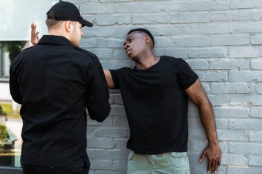 Endişeli Afrikalı Amerikalı adam üniformalı polise bakıyor, ırkçılık kavramı. 