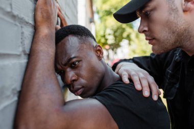 Seçici odak noktası, şapkalı bir polis Afrikalı Amerikalı 'yı sokakta alıkoyuyor, ırkçılık kavramı. 