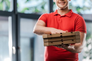 Pizza kutuları taşıyan gülümseyen teslimatçı görüntüsü. 