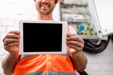 Gülümseyen elektrikçinin boş ekran ile dijital tableti göstermesinin kırpılmış görünümü  