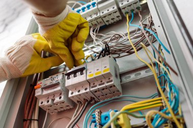 Elektrik dağıtım kutusunu tamir eden eldivenli elektrikçinin düşük açılı görüntüsü