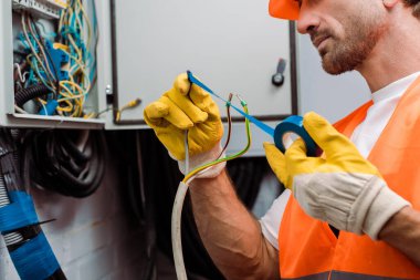 Elektrik panelinin kablolarını tamir ederken yalıtımlı bant kullanan elektrikçi görüntüsü