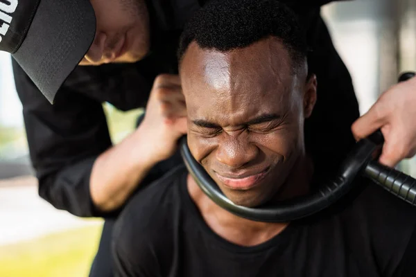Полицейский Держит Полицейскую Дубинку Горла Испуганного Африканского Американца Закрытыми Глазами — стоковое фото