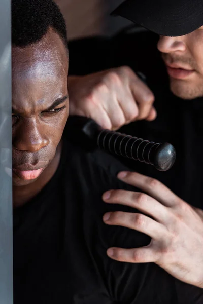 Foco Seletivo Policial Cap Segurando Truncheon Enquanto Prendia Homem Afro — Fotografia de Stock