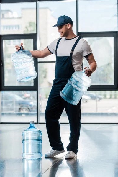 Pria Pengiriman Ceria Berseragam Melihat Botol Kosong Dekat Galon Air — Stok Foto
