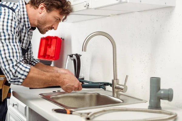Side View Handsome Repairman Using Pipe Wrench While Fixing Kitchen — Stock Photo, Image