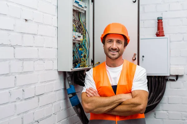 Elektrik Panelinin Yanındaki Kameraya Gülümseyen Çapraz Kollu Yakışıklı Elektrikçi — Stok fotoğraf