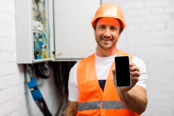 Selektivt Fokus Leende Elektriker Som Håller Smartphone Med Tom Skärm — Stockfoto