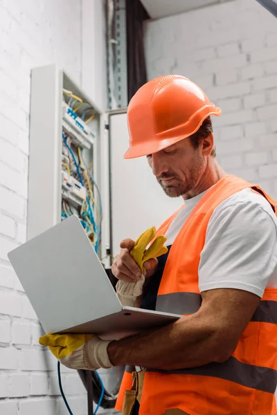 Guapo Electricista Apuntando Con Dedo Mientras Sostiene Ordenador Portátil Cerca — Foto de Stock