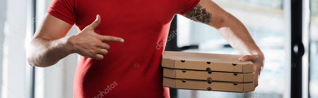 horizontal crop of delivery man pointing with finger at pizza boxes 