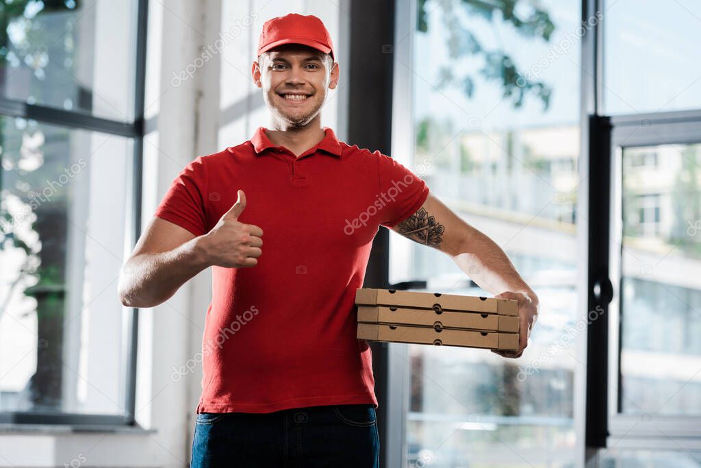 happy delivery man showing thumb up and holding pizza boxes 