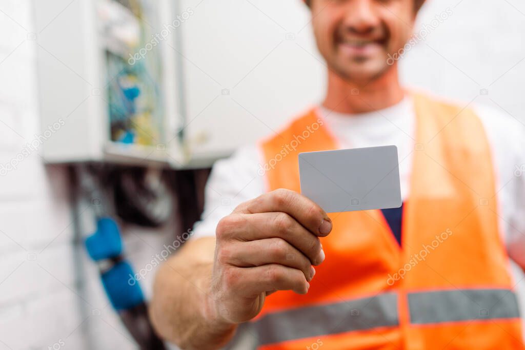 Selective focus of electrician in safety vest holding empty card 