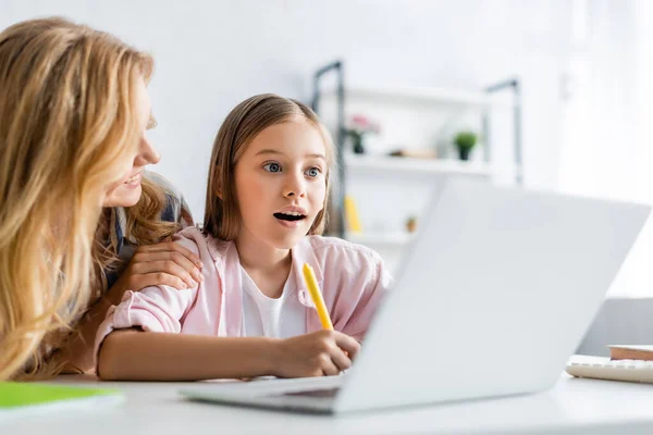 Selective Focus Smiling Woman Embracing Daughter Writing Notebook Online Education — Stock Photo, Image