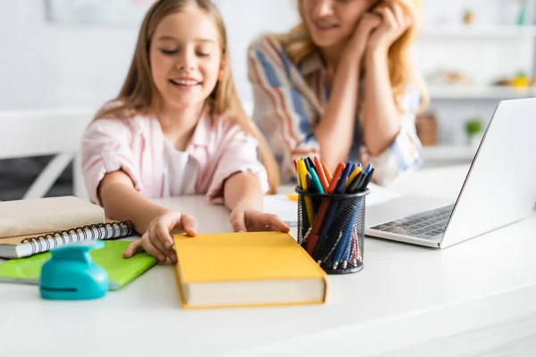 Enfoque Selectivo Del Niño Sonriente Tomando Libro Cerca Madre Ordenador —  Fotos de Stock