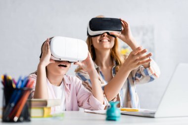 Çevrimiçi eğitim sırasında annesinin yanında vr kulaklık kullanan heyecanlı çocuğun seçici odağı 
