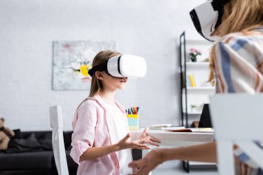 Çocuğun annesinin yanında vr kulaklık ve masadaki kırtasiye malzemesi kullanarak seçici odak noktası 
