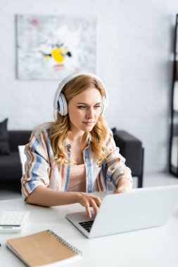 Laptop ve kulaklıklarla çalışan güzel bir kadının seçici odak noktası