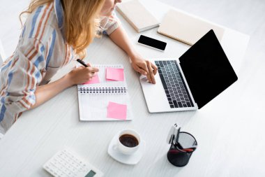 Overhead view of adult freelancer working with laptop and notebook clipart